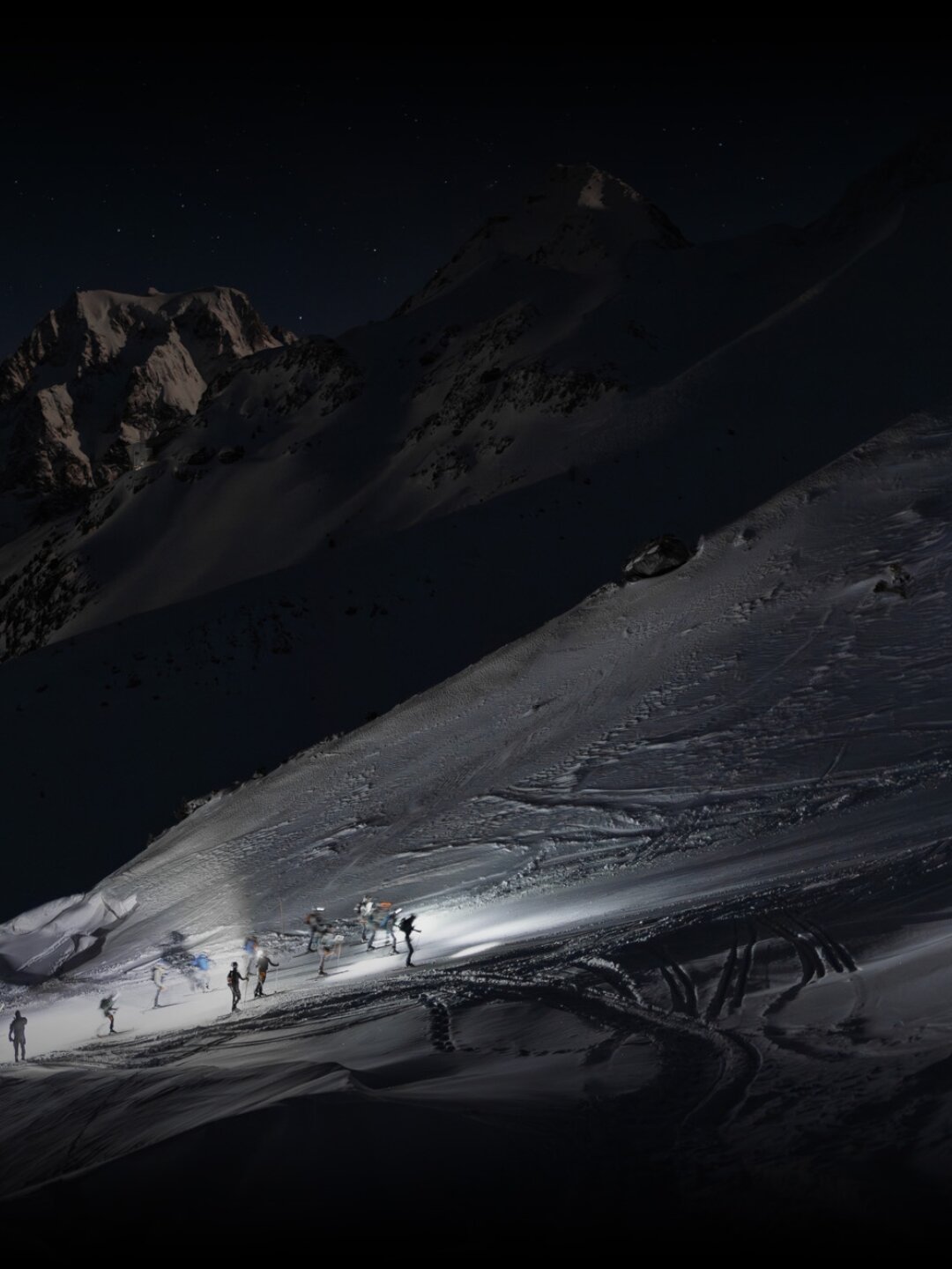 Patrouille des Glaciers at night on a snowy alpine ridge, crossing high mountain passes in Valais